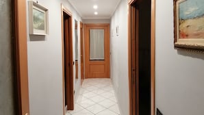 Un pasillo con suelo de baldosas, puertas de madera e iluminación empotrada.