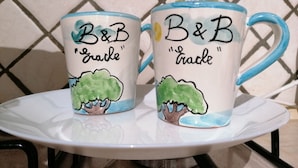 Dos tazas de cerámica, una con la inscripción "B&B" y "grade", y otra con "B&B" y "track", sobre una bandeja blanca.