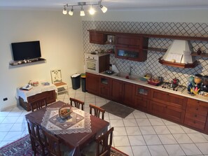 A compact kitchen with a dining area, featuring a tiled backsplash, wooden cabinets, and a built-in oven. - B&B Eracle (Ercolano)