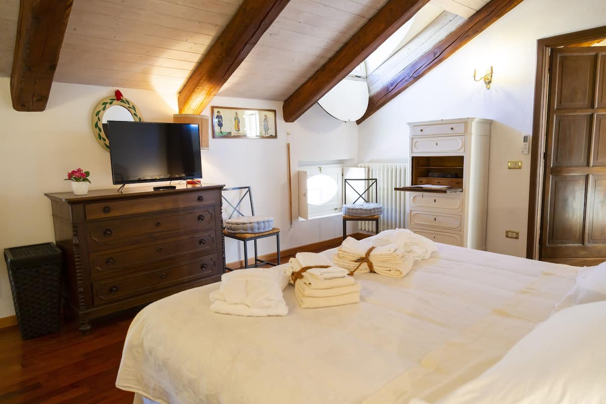 Ein Schlafzimmer mit einem großen Bett, einem Holzschrank und einem Fernseher auf einem Standfuß.