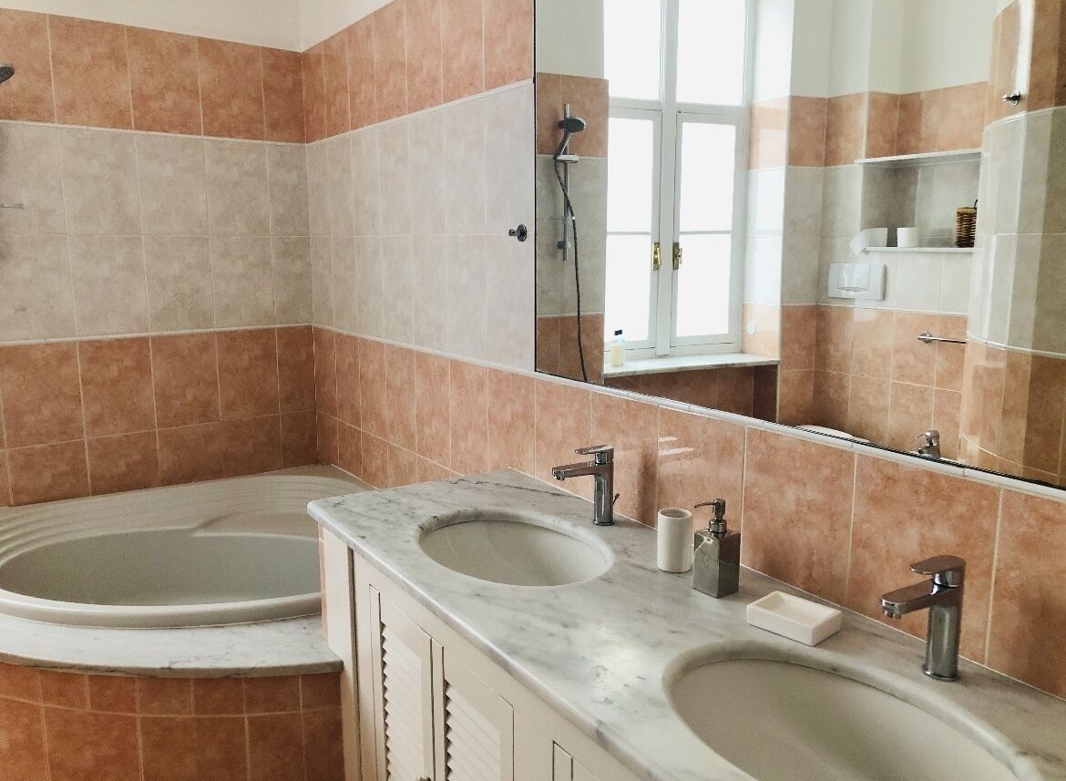A bathroom with two sinks, a bathtub, and a large mirror.