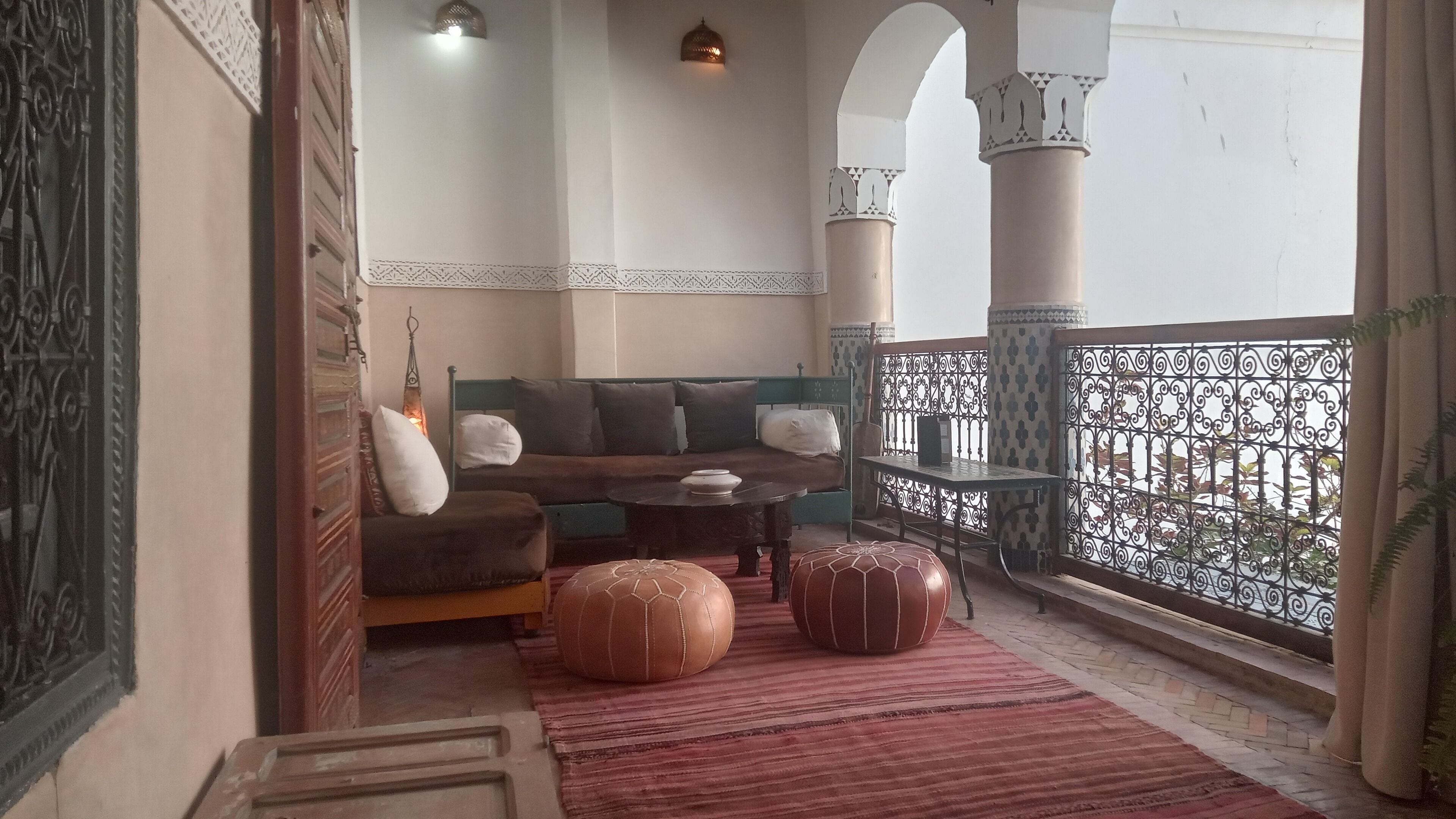 A cozy balcony with a sofa, ottomans, and a table.