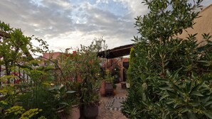 A courtyard with potted plants, a tiled floor, and a brick wall. - Riad Maizie (Marrakech)