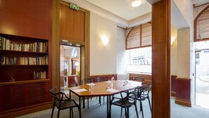 Une salle de conférence avec une longue table, des chaises, une bibliothèque et une vue sur la ville grâce à de grandes fenêtres.