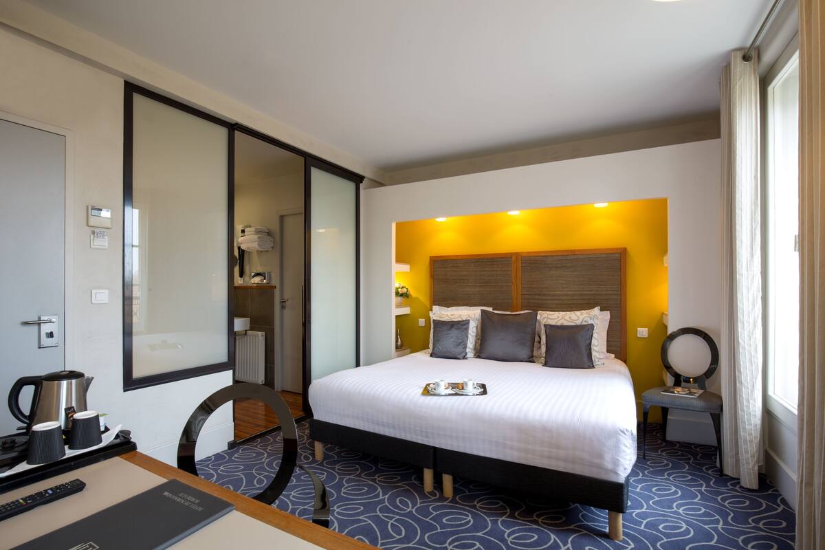 Una habitación de hotel con una cama grande, una mesita de noche y un espejo.