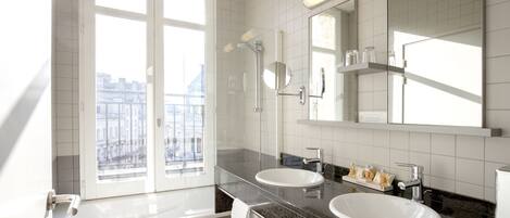 A modern bathroom with two sinks, a large mirror, and a window with a city view.