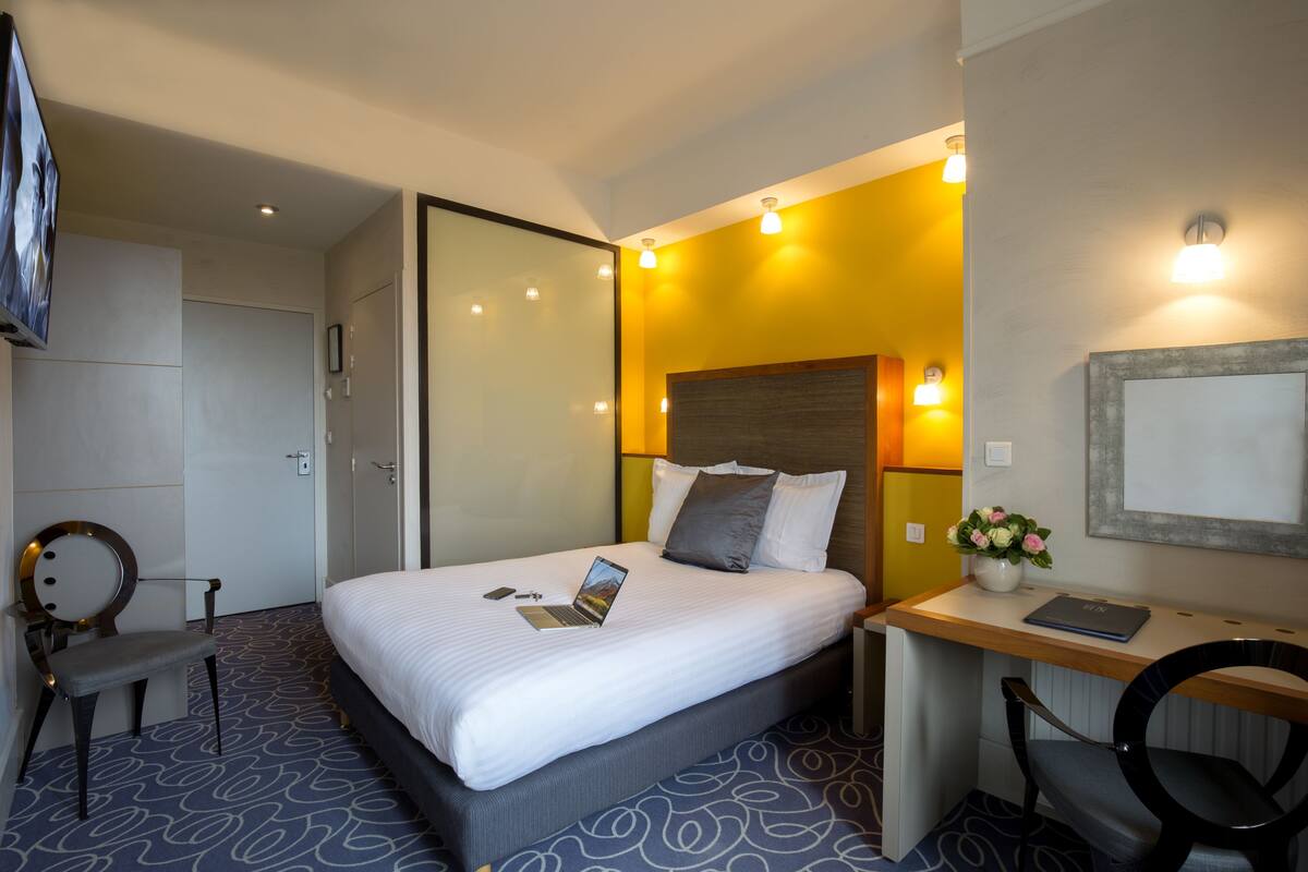 Habitación de hotel con cama, escritorio, silla y televisión.