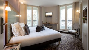 Une chambre d’hôtel avec un grand lit, un bureau, une chaise, une télévision et un balcon avec vue.