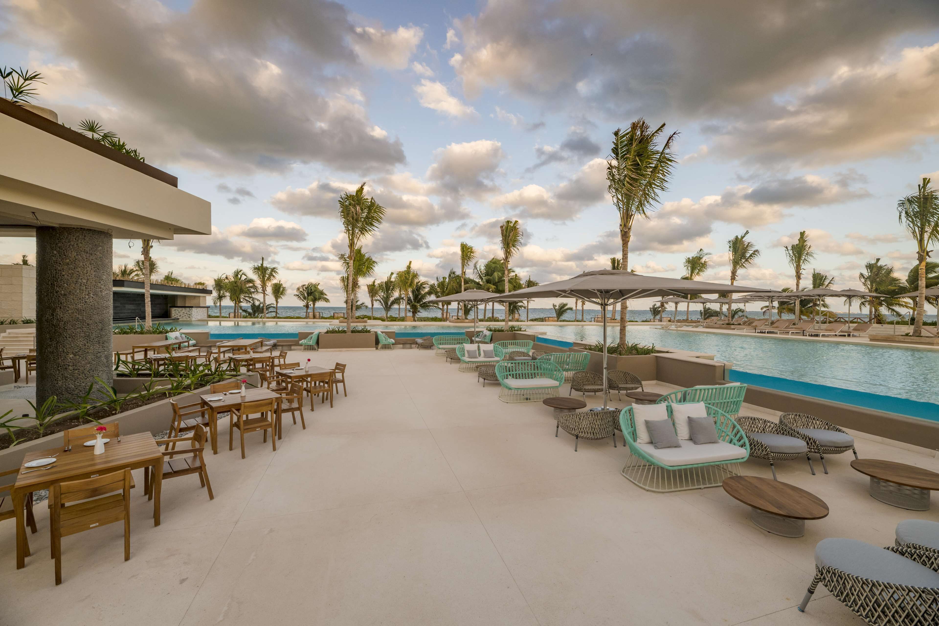A poolside area with lounge chairs, tables, and umbrellas.