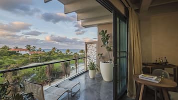Un balcón con vistas al mar, un comedor con mesa y sillas, y plantas en macetas.
