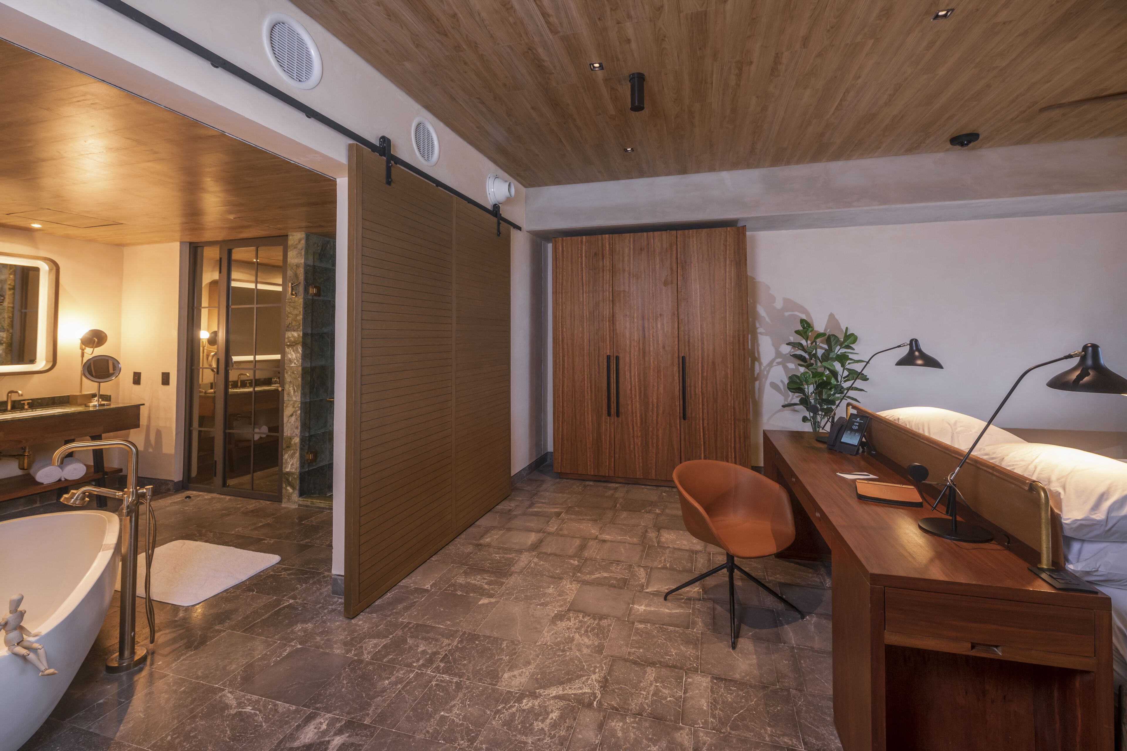 A modern bathroom with a bathtub, shower, and wooden wardrobe.