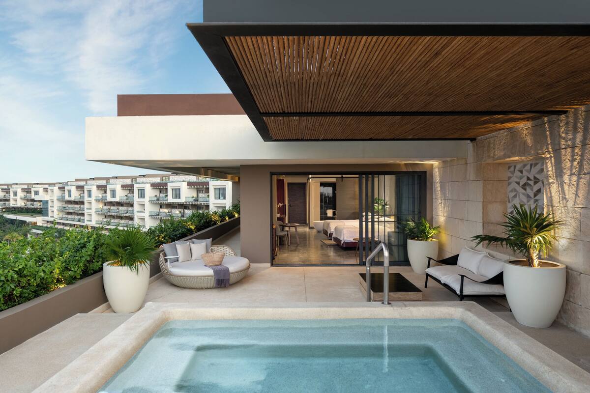 A rooftop terrace with a hot tub, seating area, and potted plants.