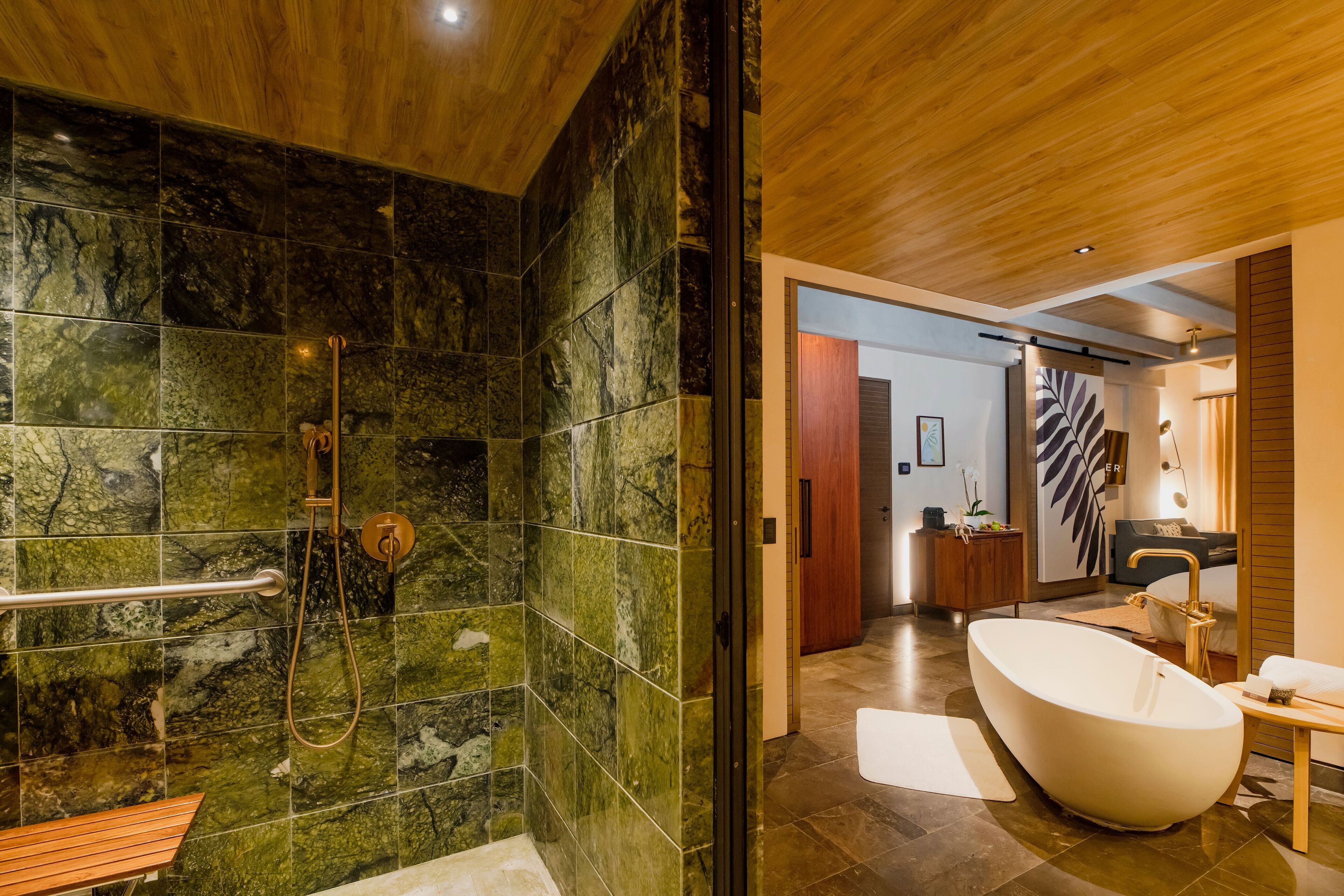 Un baño moderno con una bañera independiente, zona de ducha con puerta de cristal y un banco de madera.