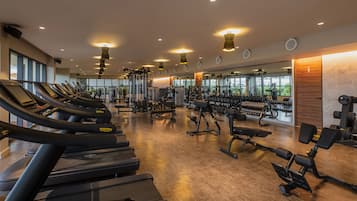 Un gimnasio con cintas de correr, máquinas de pesas y pesas sueltas.