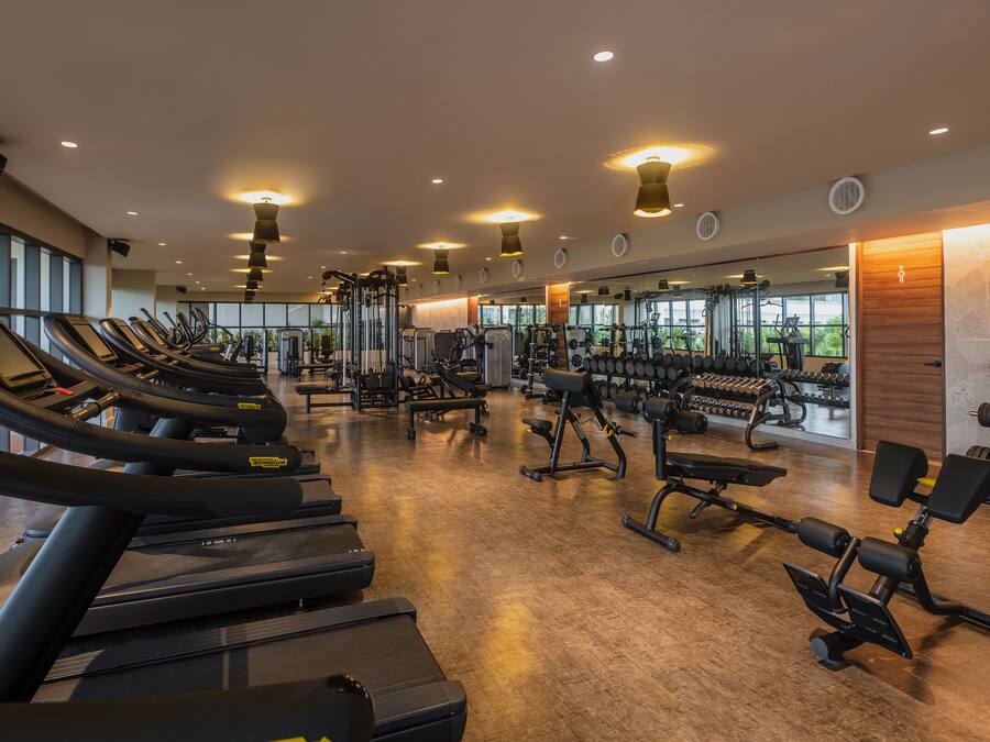 Un gimnasio con cintas de correr, máquinas de pesas y pesas sueltas.