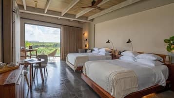Quarto com duas camas, uma escrivaninha e uma cadeira. Possui uma janela grande com vista para áreas verdes.