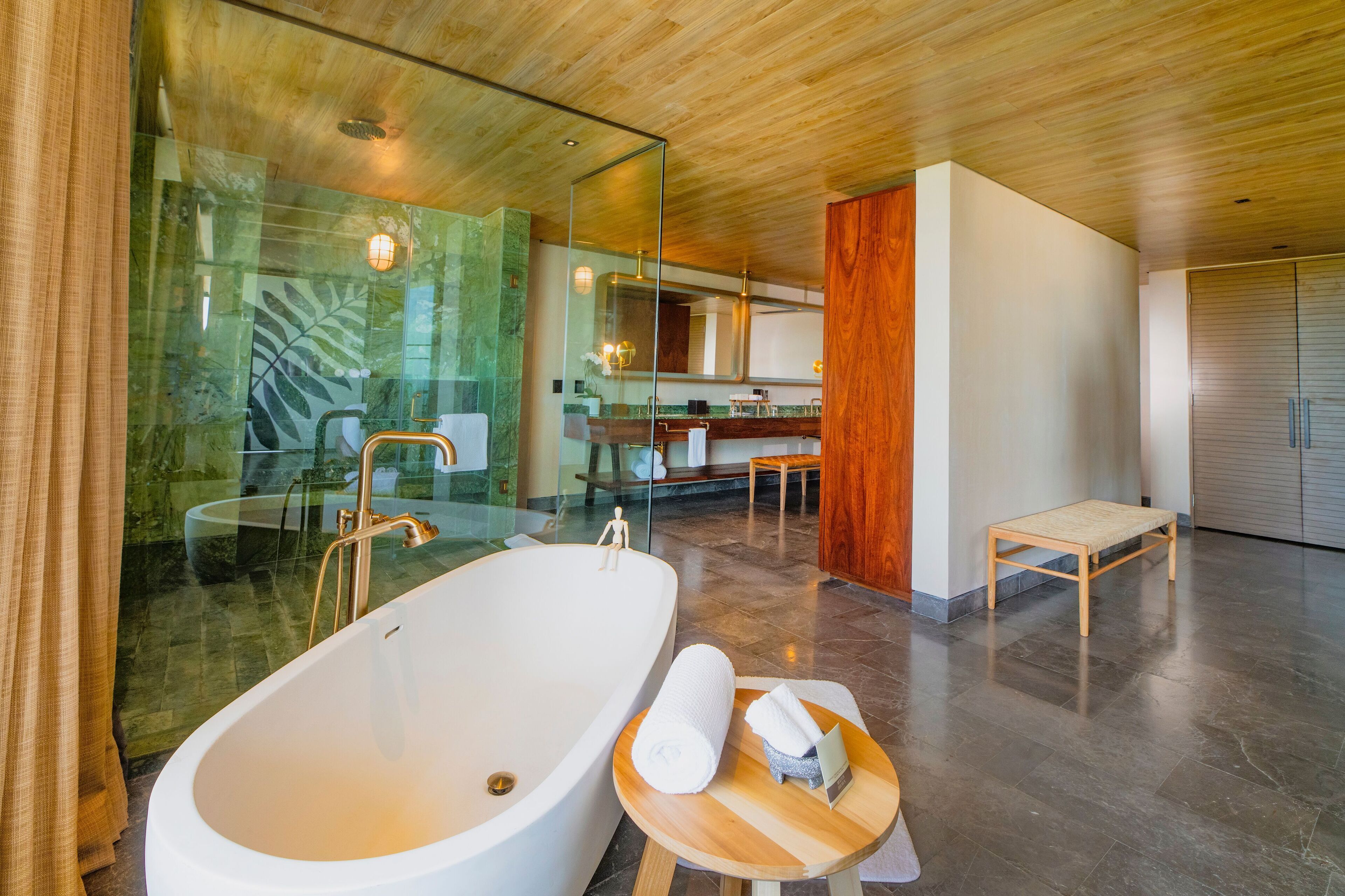 Une salle de bain moderne avec une grande baignoire, un banc en bois et une cabine de douche en verre.