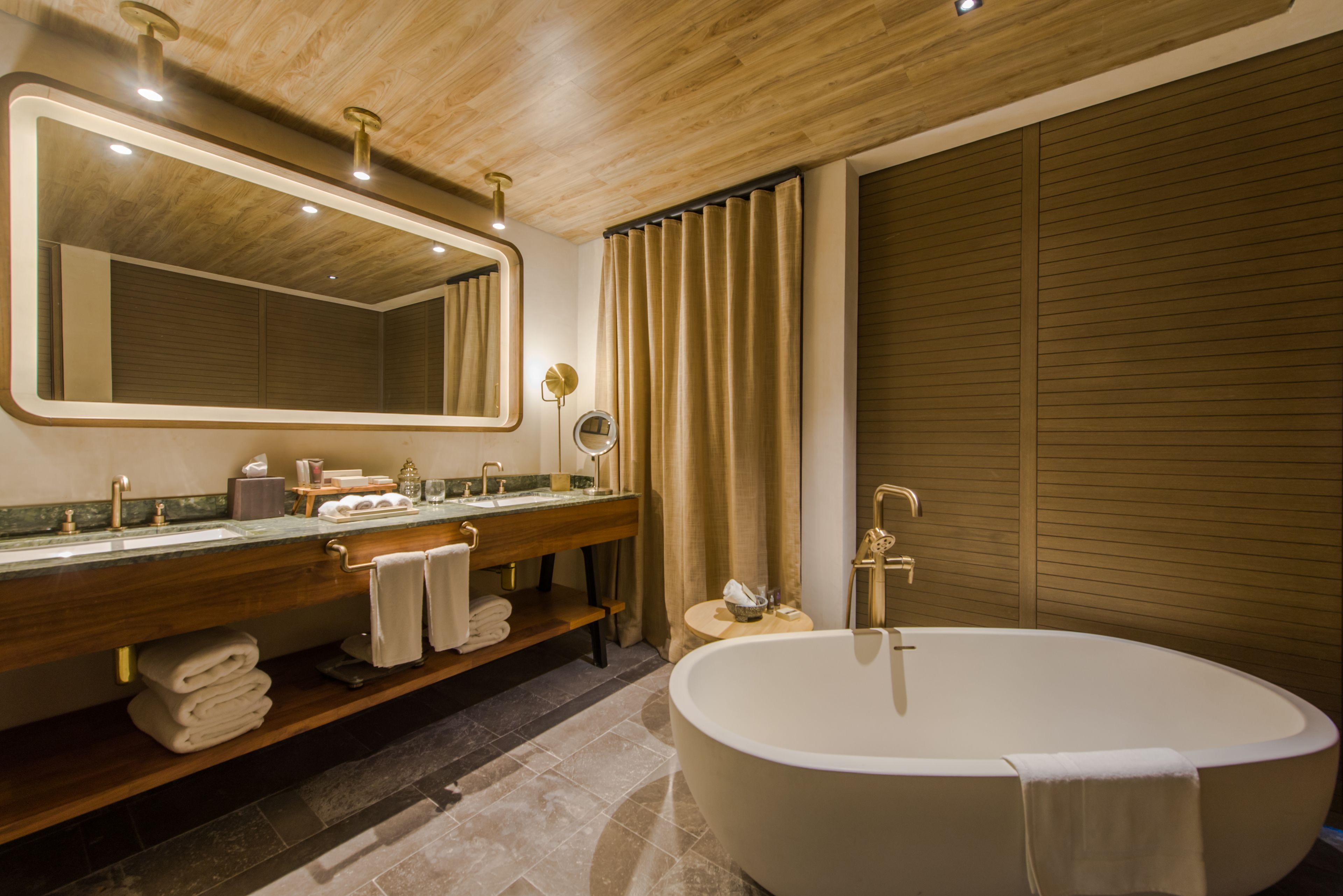 Une salle de bain moderne avec une baignoire sur pieds, un meuble-lavabo avec un miroir et une grande fenêtre avec des rideaux.