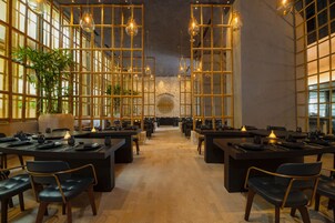 A spacious dining area with multiple tables and chairs, a central decorative wall, and hanging pendant lights.
