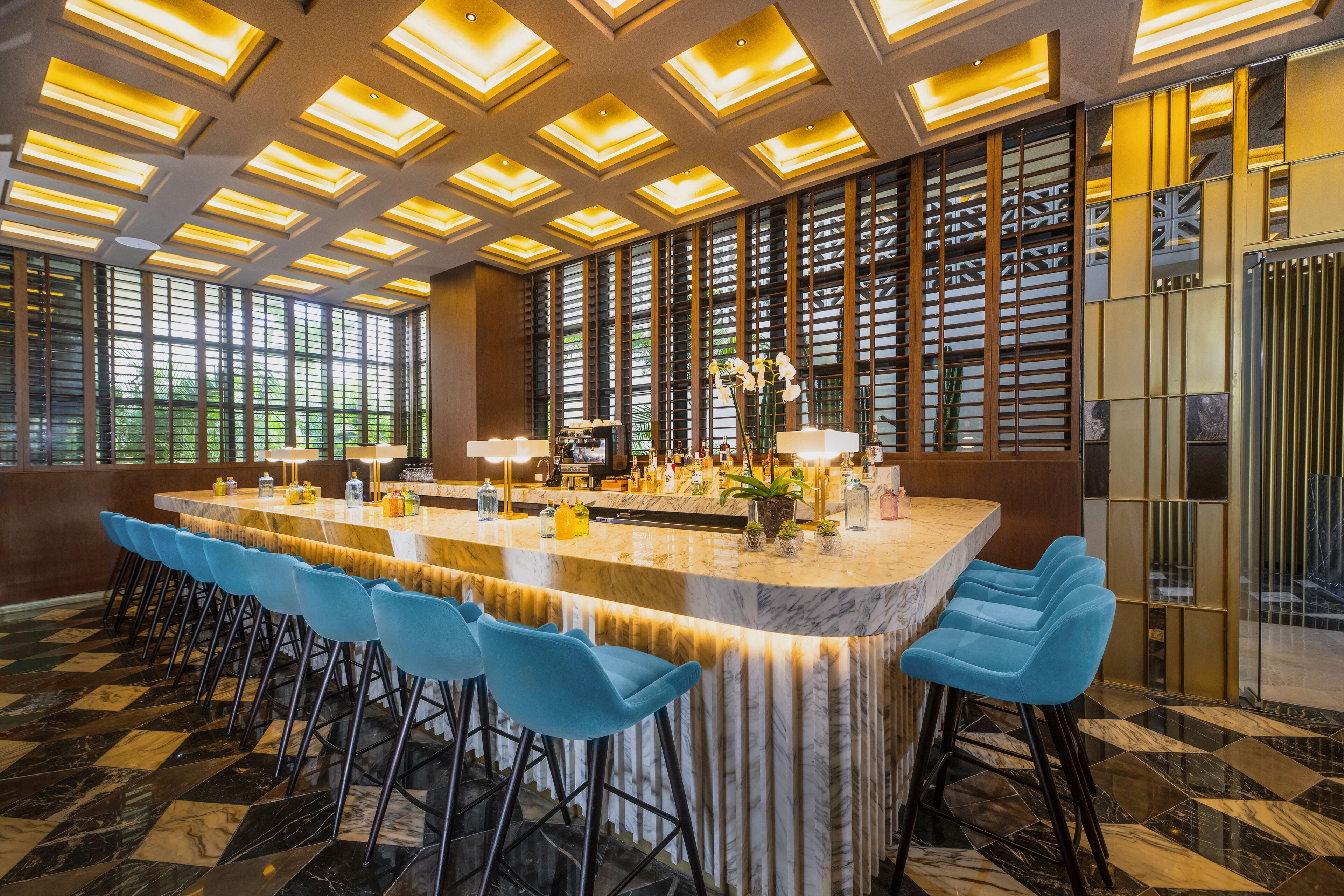 Angolo bar con bancone in marmo, sgabelli blu e un elemento decorativo.