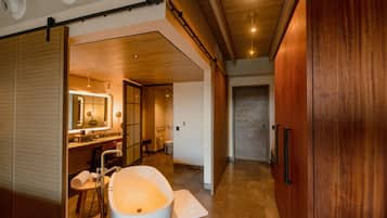 A modern bathroom with a large bathtub, a vanity with a mirror, and a wooden door.