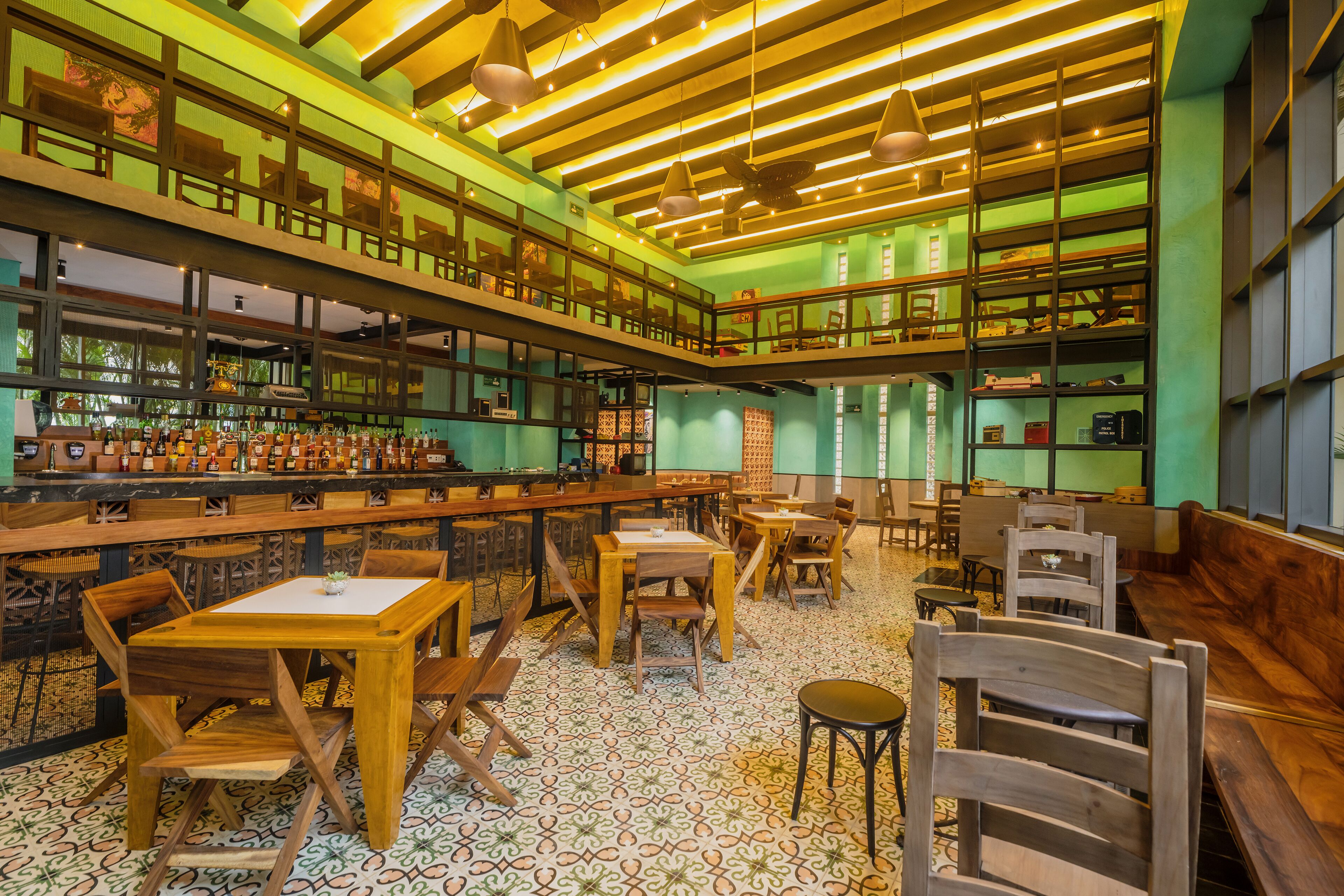 Un vaste espace bar offrant de nombreuses options de sièges, notamment des tables et des chaises, ainsi qu’une variété de bibliothèques remplies de livres et d’objets décoratifs.
