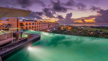Un resort con piscina infinita, mobiliario exterior y vistas al océano al atardecer.