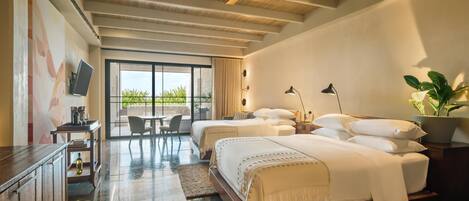 A hotel room with two beds, a desk, a chair, a TV, and a large window with a view of greenery.