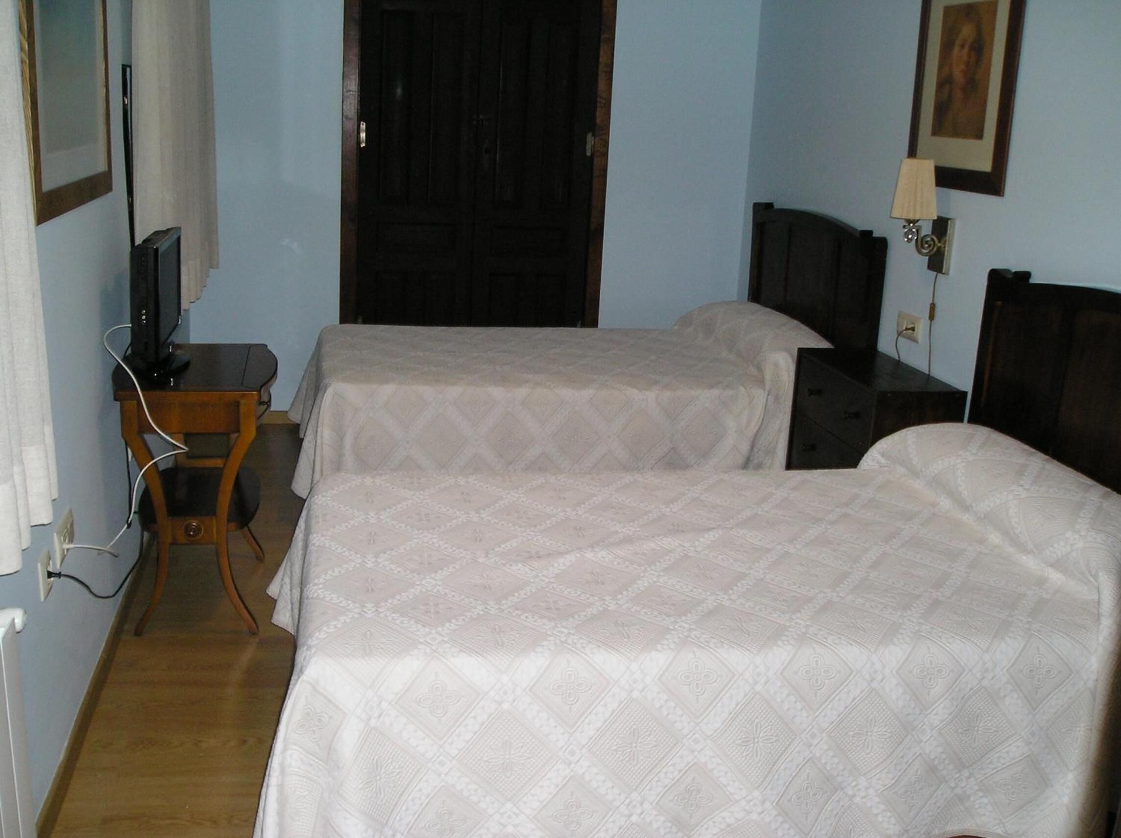 A room with two beds, a desk, a television, and a door.