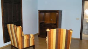 Una habitación con dos sillones a rayas, un armario de madera y una puerta.