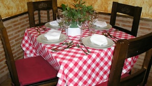 Una mesa de comedor dispuesta con platos, vasos y cubiertos, rodeada de sillas de madera.