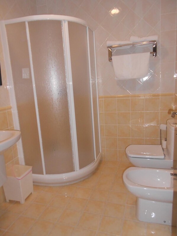 A bathroom with a glass-enclosed shower, a toilet, and a sink. - Hostal Ciudad Antigua (Hellin)