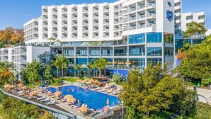 Un hôtel doté de nombreux balcons, d’une piscine et d’un aménagement paysager luxuriant.