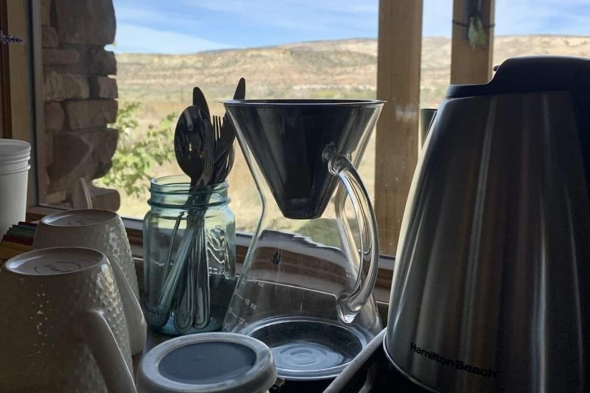 A kitchen area with a coffee maker, a kettle, and utensils.