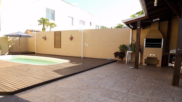 Un giardino con piscina, un pontile in legno e una zona barbecue.