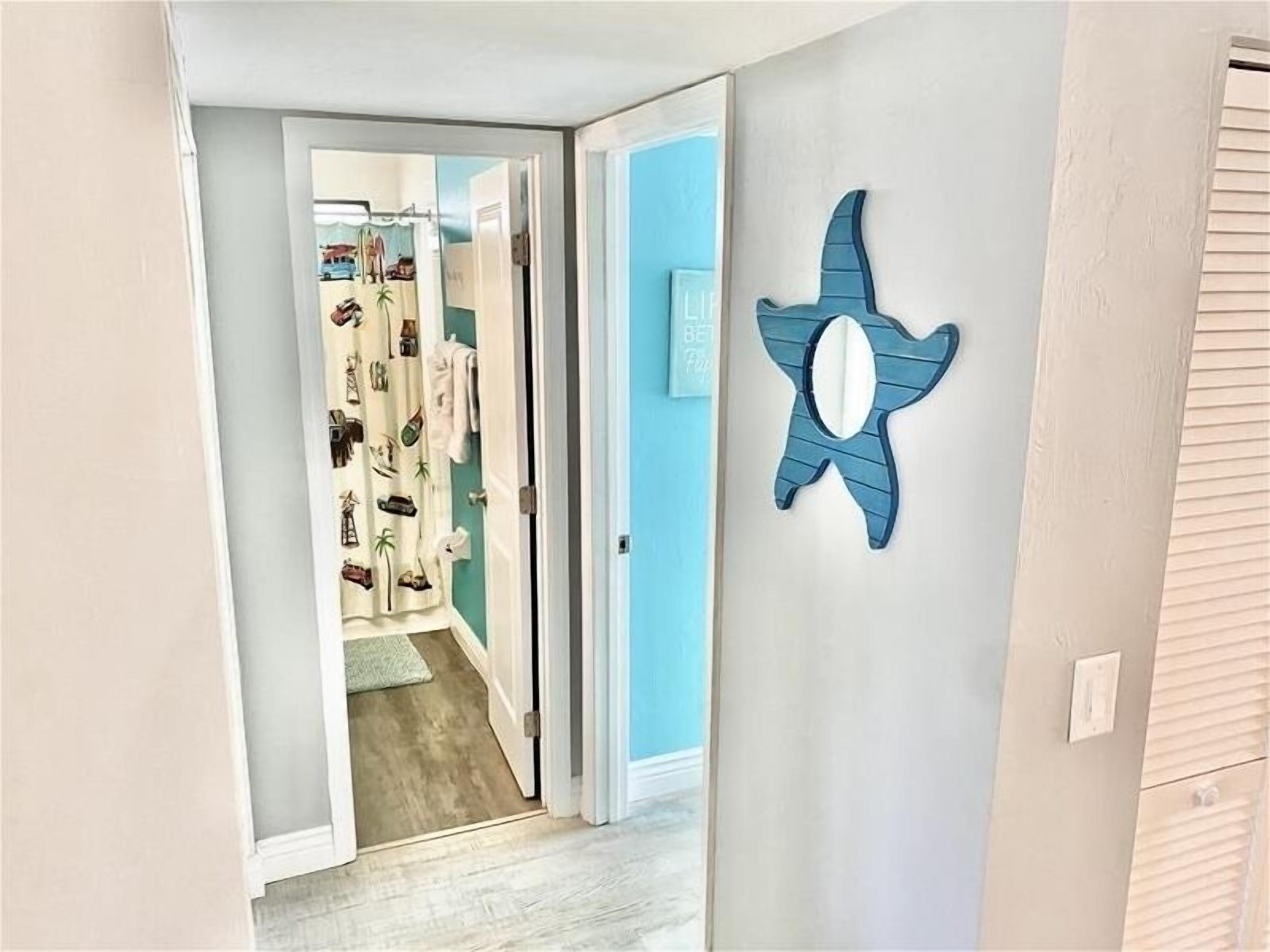 A hallway with a blue wall and a decorative star-shaped mirror.