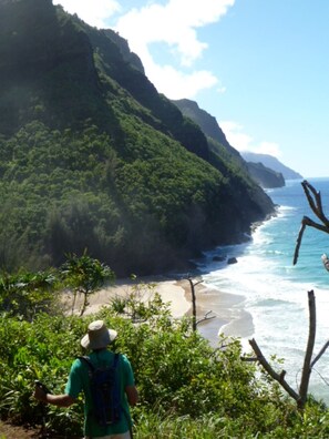 A person hiking on a trail overlooking a beach with a mountain in the background. - Among the Closest Homes to Poipu Beach • 3BR/3BA with AC and Views (Koloa)