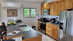 Una cocina con armarios de madera, un refrigerador de acero inoxidable, un microondas y una estufa.