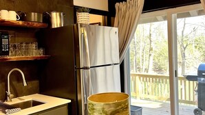 Una cocina moderna con refrigerador, lavamanos e iluminación colgante.