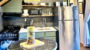 Una cocina moderna con techo de madera, refrigerador de acero inoxidable, microondas y estufa.