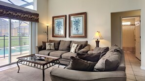 A living room with a glass coffee table, two sofas, a ceiling fan, and two framed pictures on the wall. - 4 BR Pool Home/Close to Disney/Universal/Pool/Spa/BBQ/Wifi/Guard Gated Resort (Kissimmee)