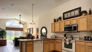 A spacious kitchen with wooden cabinets, a large island, stainless steel appliances, and a view to the outside. - 4 BR Pool Home/Close to Disney/Universal/Pool/Spa/BBQ/Wifi/Guard Gated Resort (Kissimmee)