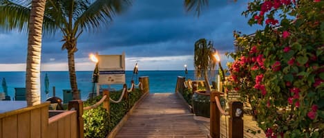 A wooden pathway leading to a beach with palm trees and a sign for a national park.