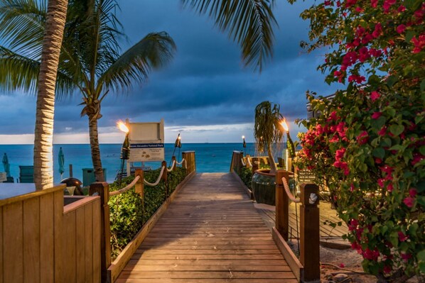 A wooden pathway leading to a beach with palm trees and a sign for a national park.