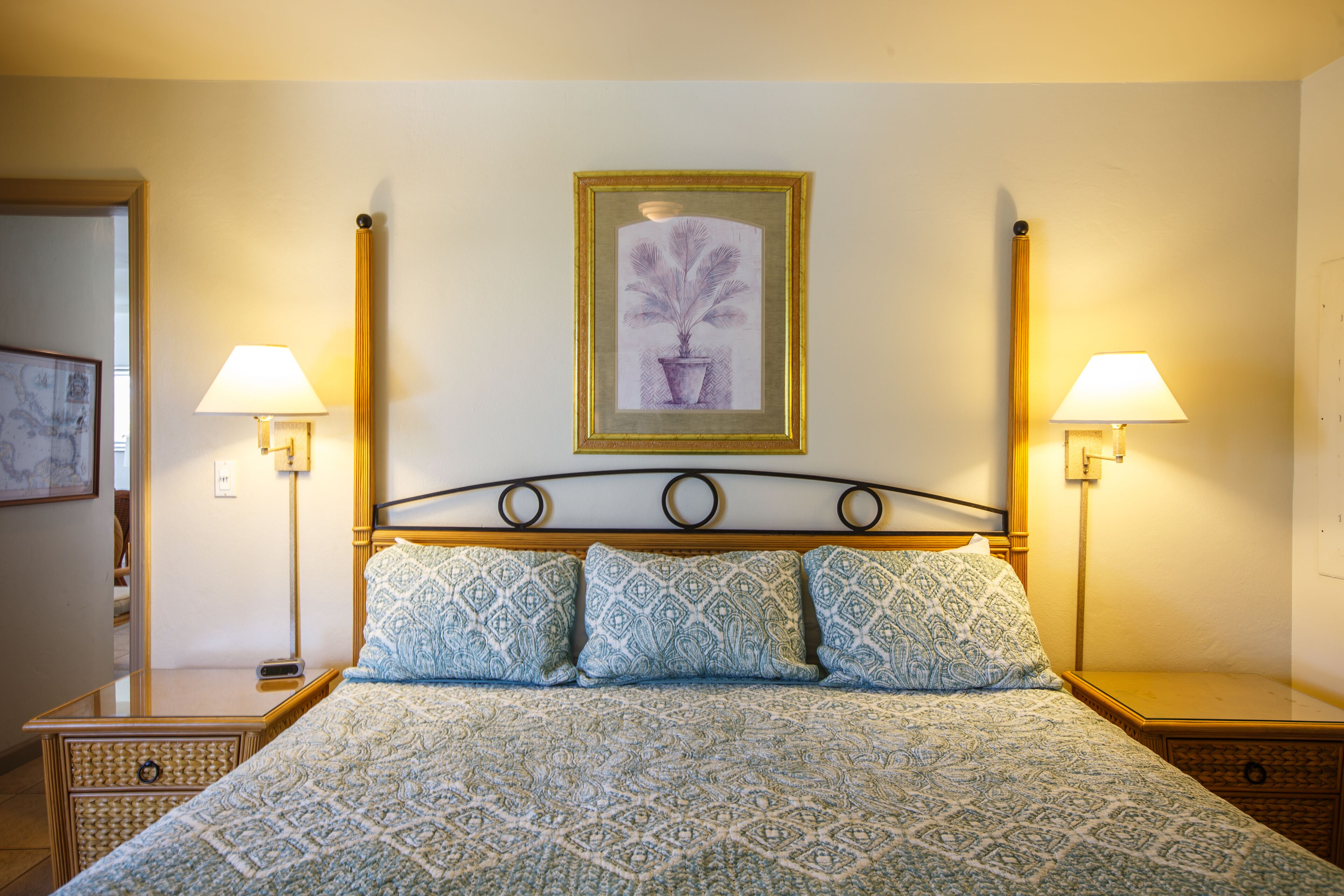 A neatly made bed with patterned bedding, two bedside lamps, and a framed artwork on the wall.