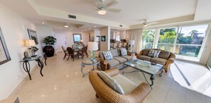 A spacious living area with a glass coffee table, wicker furniture, and a view of the outdoors. - Relax in your very own private paradise (Providenciales)