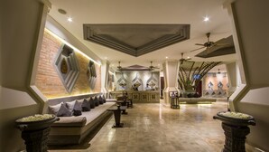 A spacious lobby with a modern design, featuring a seating area with a sofa and chairs, a reception desk, and decorative wall elements. - Central Residence Suite  (Krong Siem Reap)