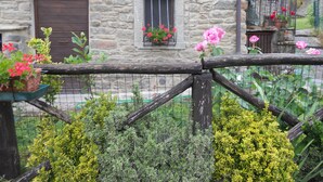 Un bâtiment en pierre avec une porte en bois, une fenêtre ornée de fleurs et une clôture en bois.