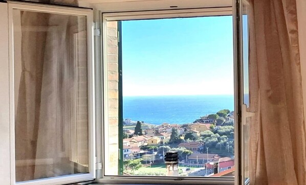 A window with a view of a coastal town and the sea. - Old stone house with sea view (pompeiana)