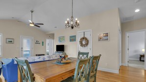 A dining area with a wooden table, four chairs, a chandelier, and a ceiling fan. - Bonne Mer: Three bedroom, two bathroom house in Oak Island close to shopping and (Oak Island)